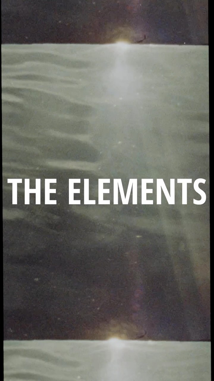 Abstract seascape with the text 'The Elements' in white, showing a sunlit body of water beneath a blurred dark horizon.