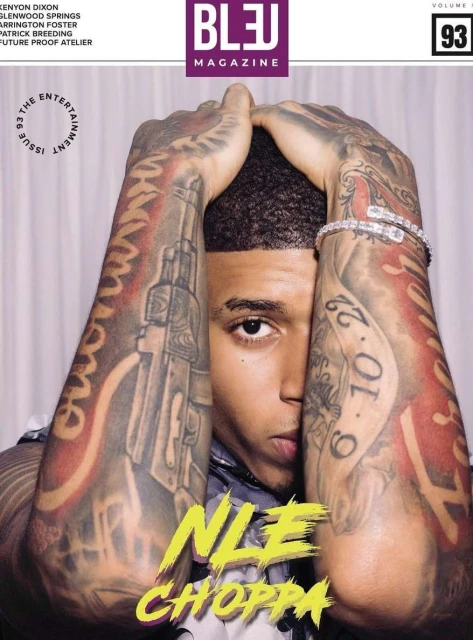 Magazine cover featuring a close-up of NLE Choppa, with his hands raised above his head, displaying multiple arm tattoos and a diamond bracelet.