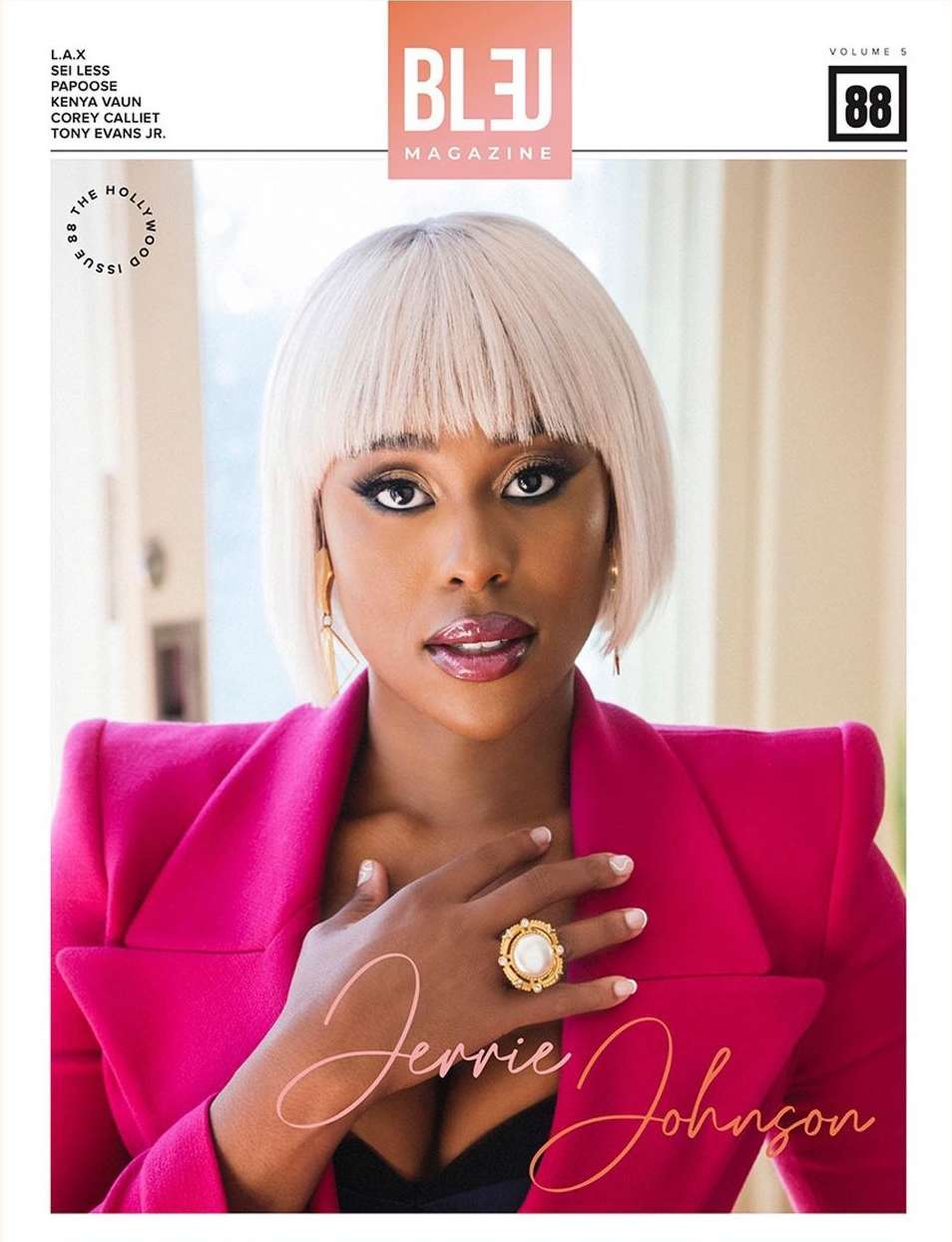 Black woman wearing a bright pink blazer and large gold ring, with short blonde bob hair and bangs, photographed by Andrew Zaeh.