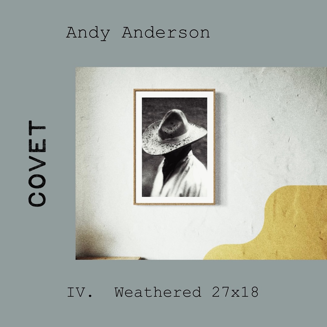 Black and white photographic print of a person in a wide-brimmed hat on a textured wall. The art piece is framed in light brown wood.