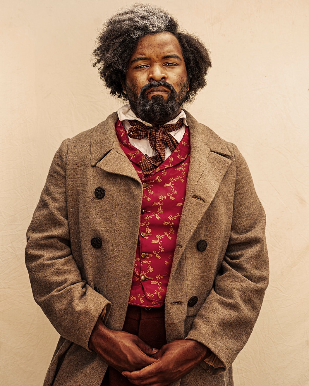 Portrait of a serious-looking adult male with graying hair, a beard, and mustache, wearing a vest and coat against a neutral background.