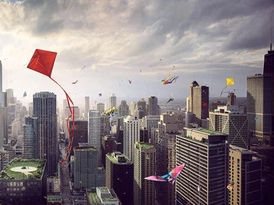 Aerial view of a dense city skyline filled with numerous colourful kites flying between tall skyscrapers under an overcast sky.