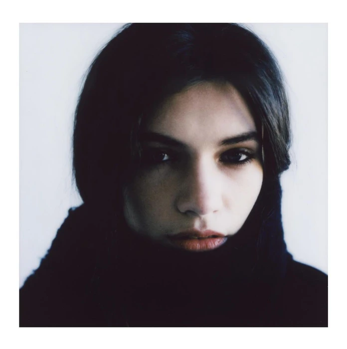 Close-up portrait of a woman with dark hair and dark turtleneck sweater against a white seamless background