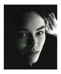 Close-up monochrome portrait of a model with dark hair posing in deep shadow by Andy Harrington in Paris.