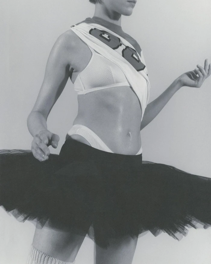 Model wearing a black tutu skirt and layered athletic tops against a neutral background.