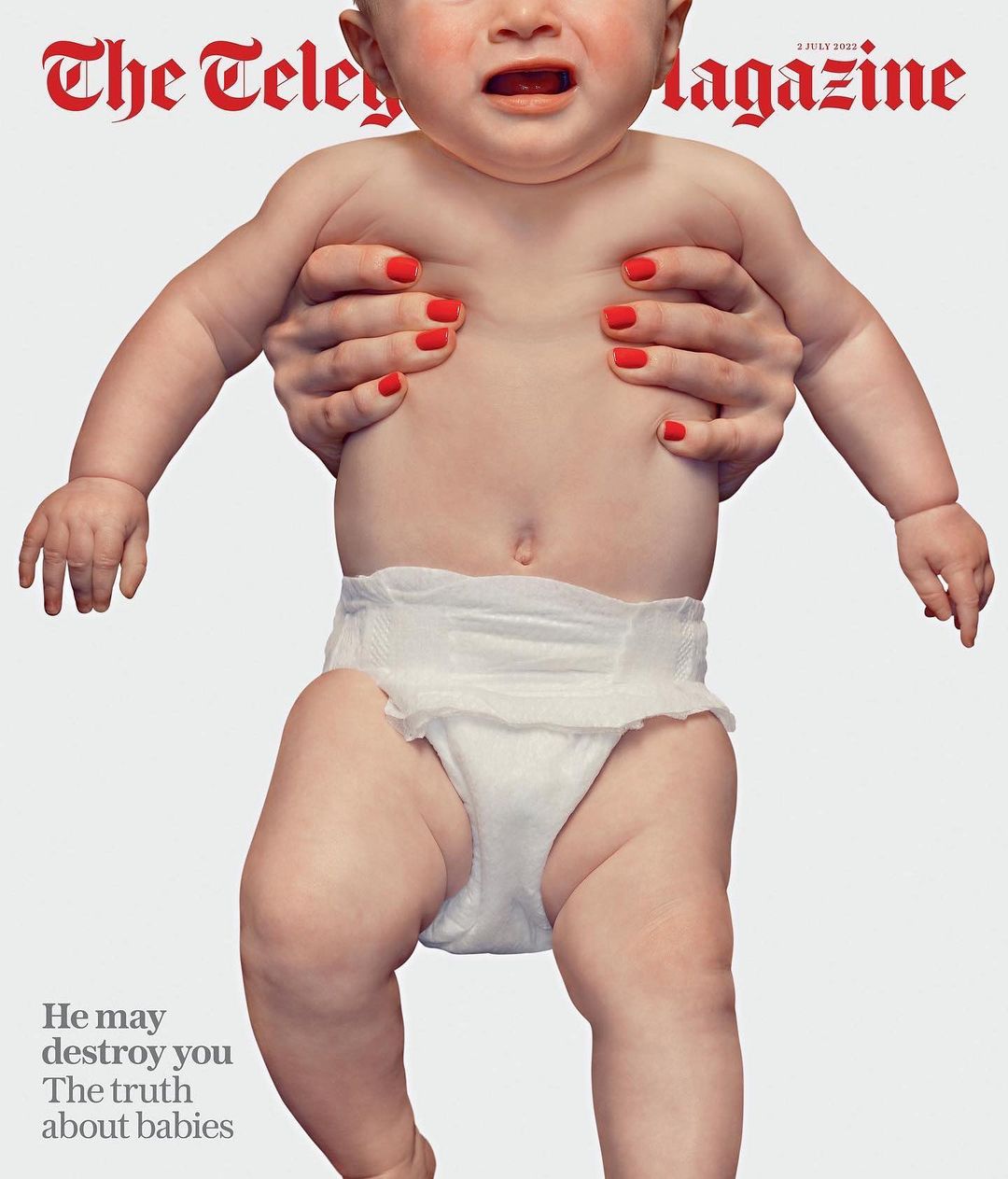 Magazine cover featuring a baby held by adult hands, showcasing the infant's expression and diaper against a white backdrop.