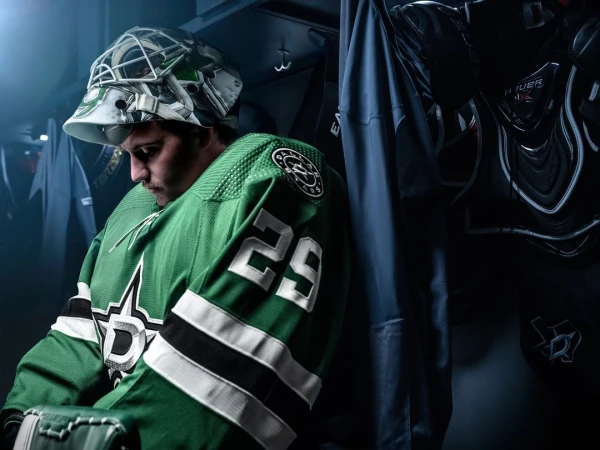 Hockey player in green and black uniform with mask in locker room, showcasing sports and athletic wear.