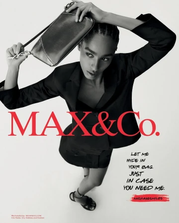 Black and white fashion advertisement for Max&Co. features an adult woman in a dark suit holding a shiny clutch overhead.