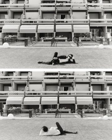 Split-frame black and white editorial image of a person reclining on grass in front of a multi-story residential building facade.