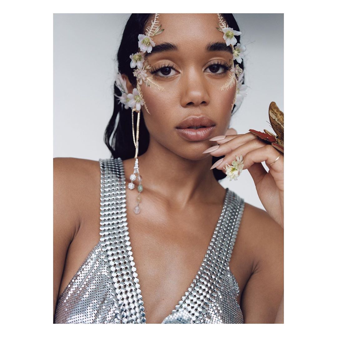 Close-up shot of a woman with flowers and beaded jewelry. She wears a silver top and has fair skin and long dark hair.