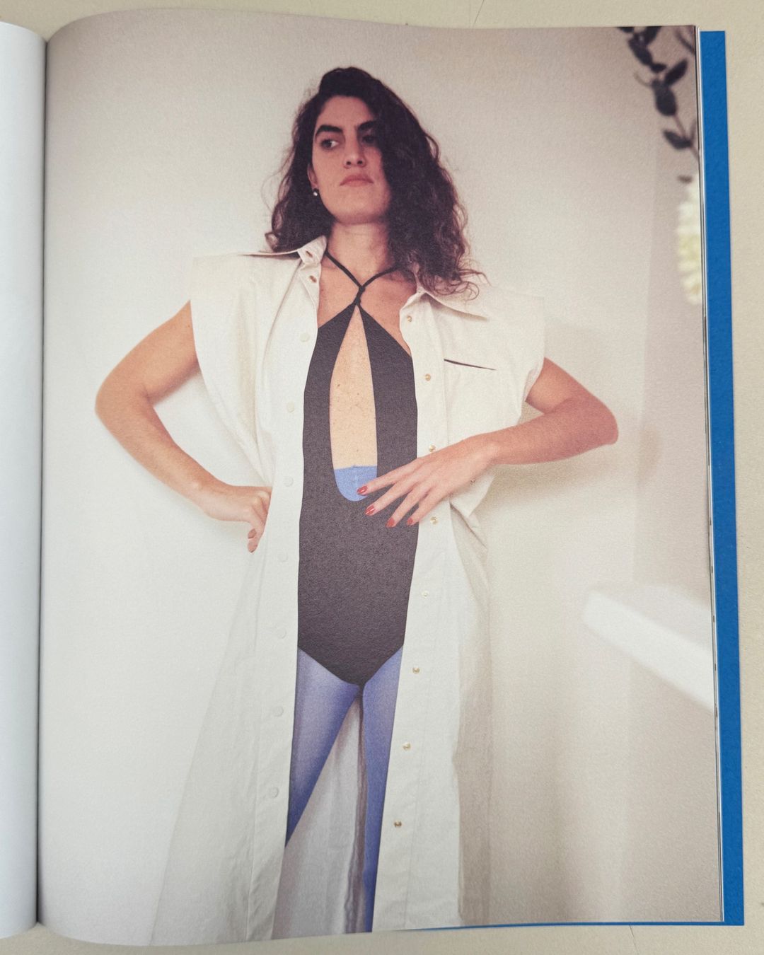 Woman wearing sleeveless white button-down coat and black one-piece bodysuit photographed by Angelo Pennetta.
