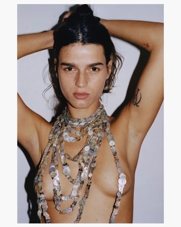 Woman with arms raised wearing a layered button necklace against a white background
