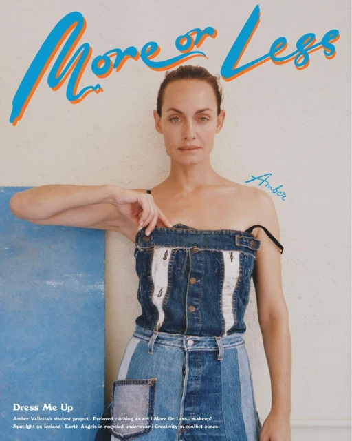 Amber Valletta poses in a denim outfit in front of a blue panel and white wall with More or Less magazine title, shot in portrait.