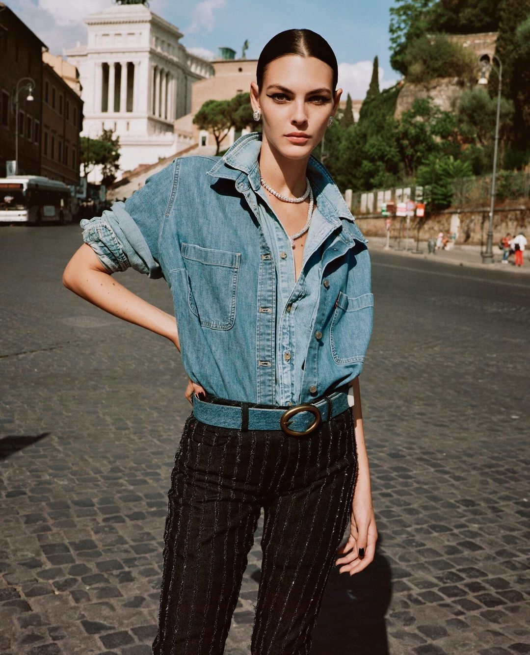 Fashionable woman in denim shirt and embellished trousers in urban setting, Rome, Italy. Shoulder-length shot, daytime outdoor scene.