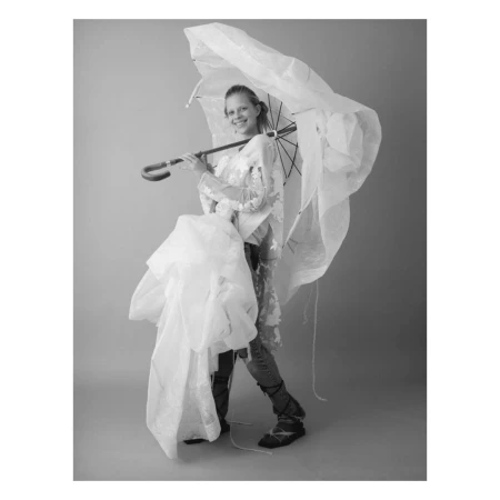 Smiling woman in patterned top holding a large white umbrella over her shoulder