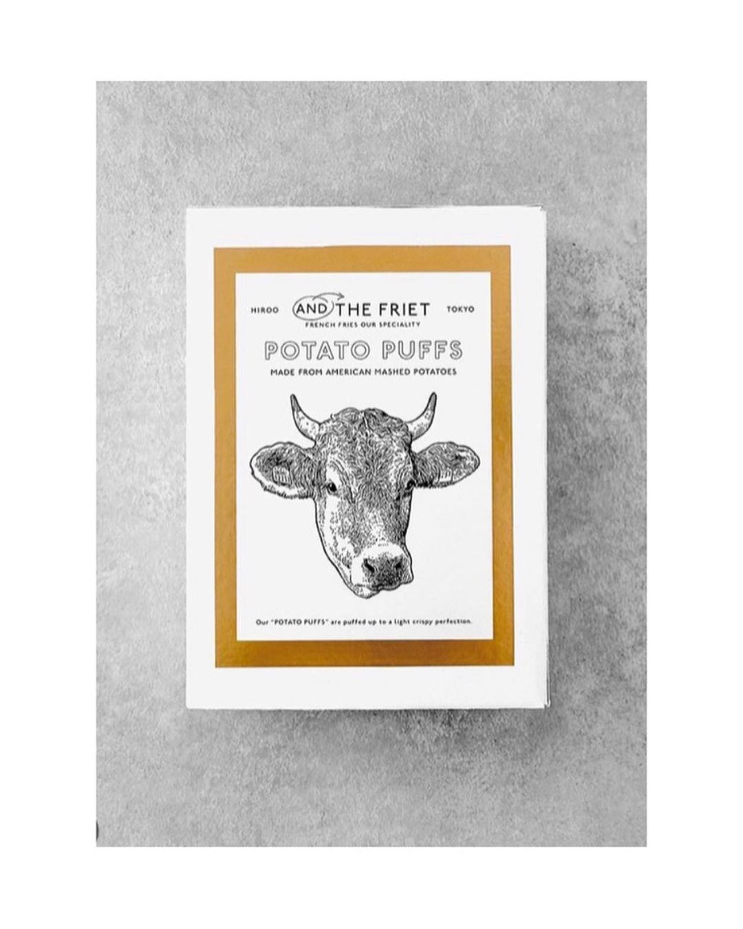 Box of Potato Puffs from AND THE FRIET, Tokyo, featuring an illustration of a cow's head on a white background with gold accents.