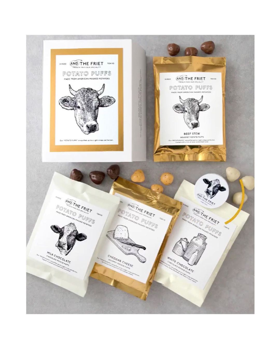 Multiple packs and a box of potato puffs featuring illustrations of a cow and cheese, displayed against a neutral backdrop.
