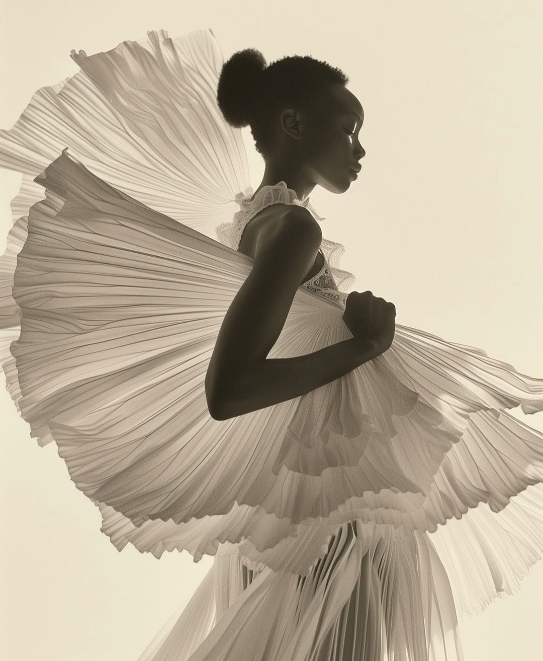 Monochromatic portrait of a Black female model in a flowing, pleated dress against a cream backdrop, captured in a studio setting.