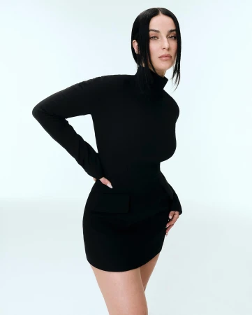 Elegant adult woman in black turtleneck dress strikes a pose against a light background in a studio setting for fashion. 