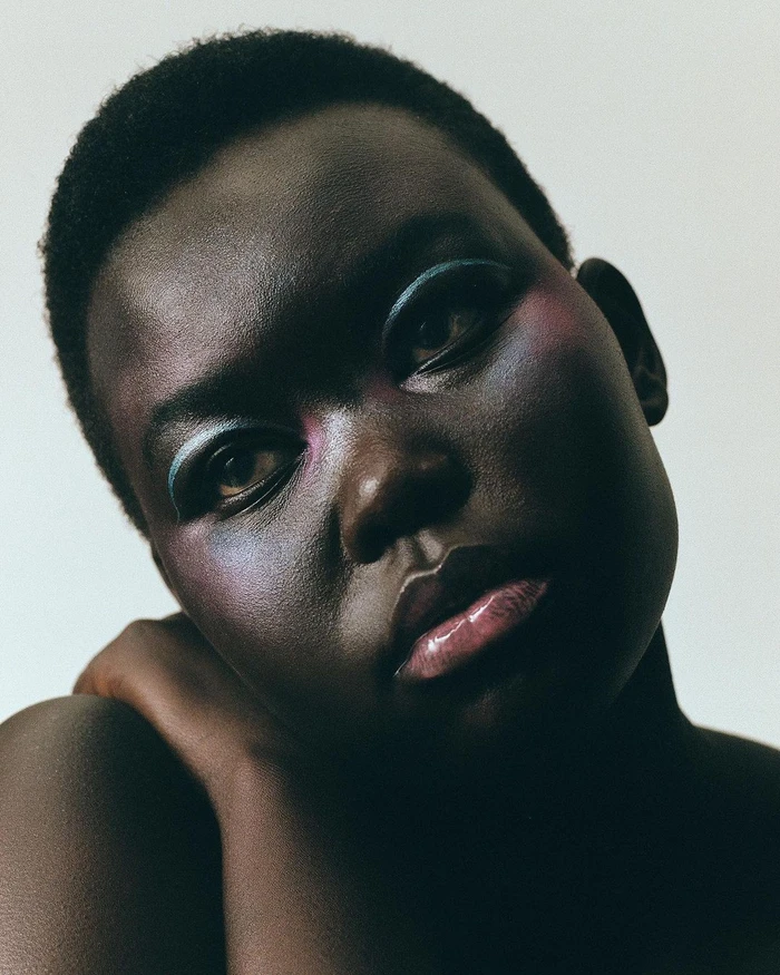 Close-up portrait of a Black woman with short hair and colorful editorial eye makeup, shot by Anna Daki in Paris.