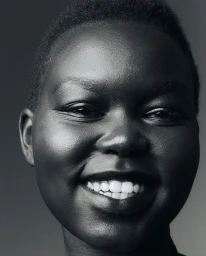 Close-up black and white portrait of a smiling Black woman with short hair photographed by Anna Daki