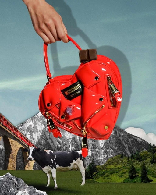 Collage of a heart-shaped Moschino purse held by a hand, with a cow standing in a landscape of rolling hills and snow-capped mountains.
