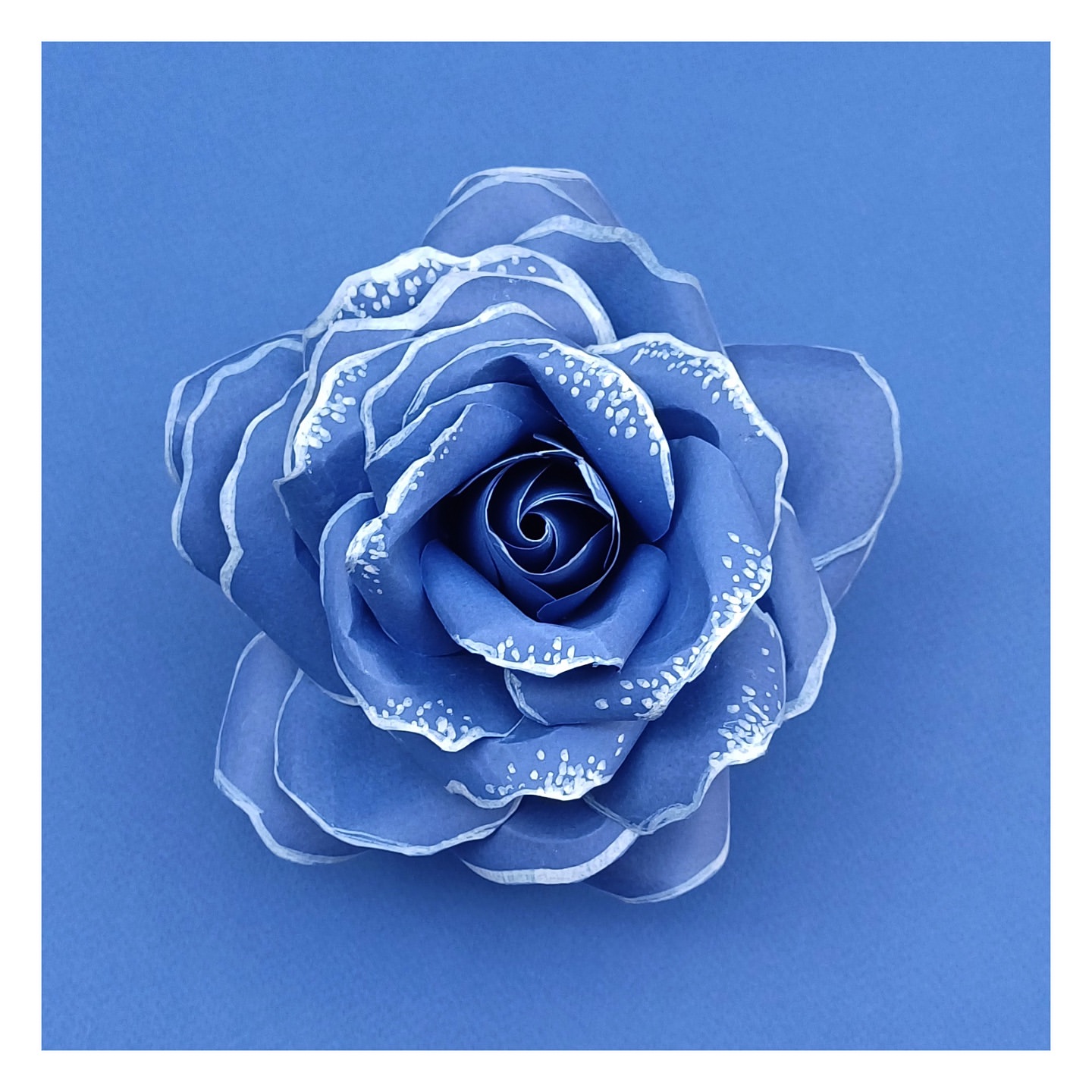 Detailed close-up of a handcrafted blue rose with subtle white accents, set against a matching blue background, highlighting textures.