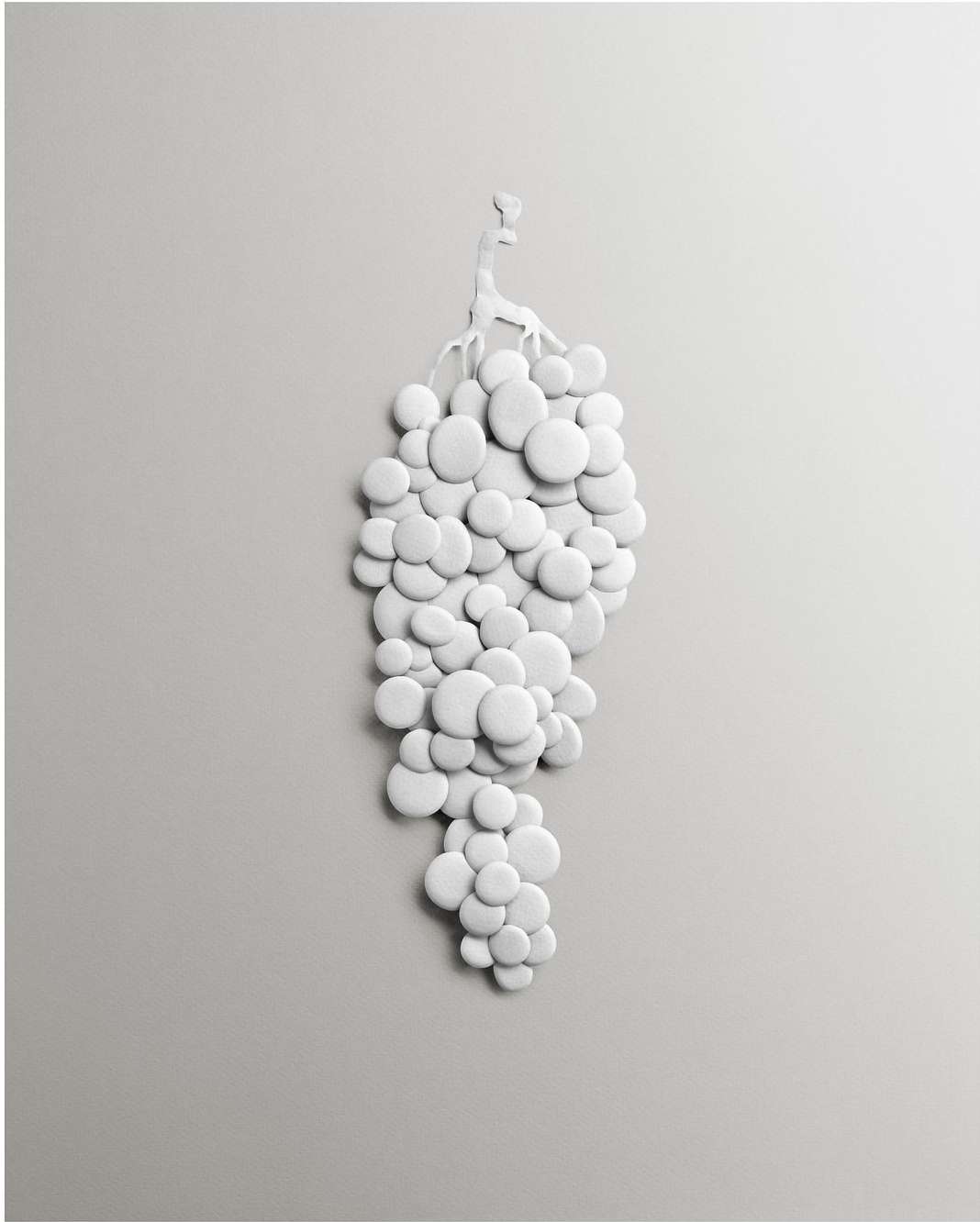 Stylized monochrome photograph of a bunch of white grapes made from circular shapes, against a pale-gray background, creating an abstract food still life.