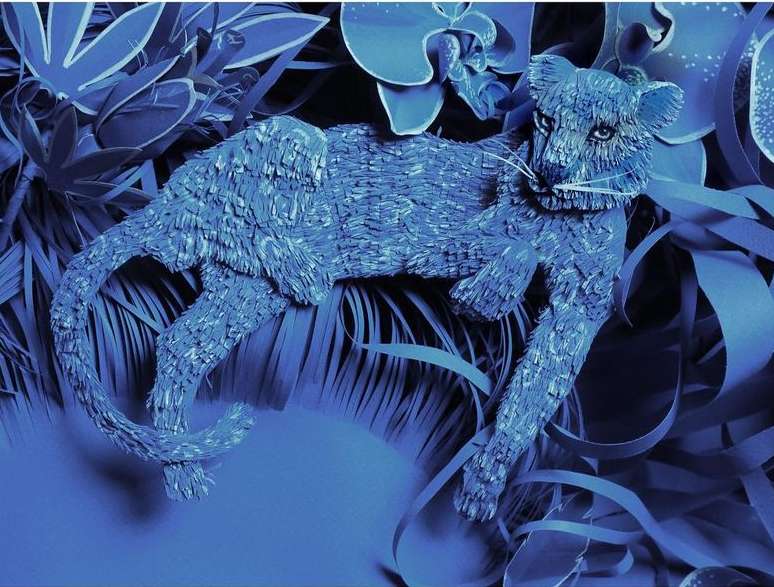Monochromatic blue paper art of a resting jaguar surrounded by layered paper plants and flowers. Fine art and nature & wildlife themes.