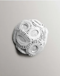 Intricate white paper sculpture with layered circular patterns set against a plain light grey gradient background.