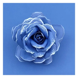 Top-down view of a handmade blue paper flower with white painted edges on a solid blue background