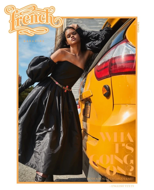 Elegant woman in a black dress posing next to a yellow taxi with magazine cover text, capturing a blend of fashion and urban lifestyle.
