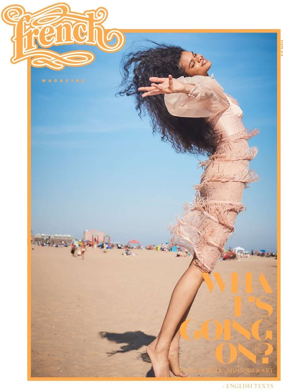 Magazine cover featuring a Black woman in a fringed dress on a beach with people enjoying a sunny day. The magazine title is French.
