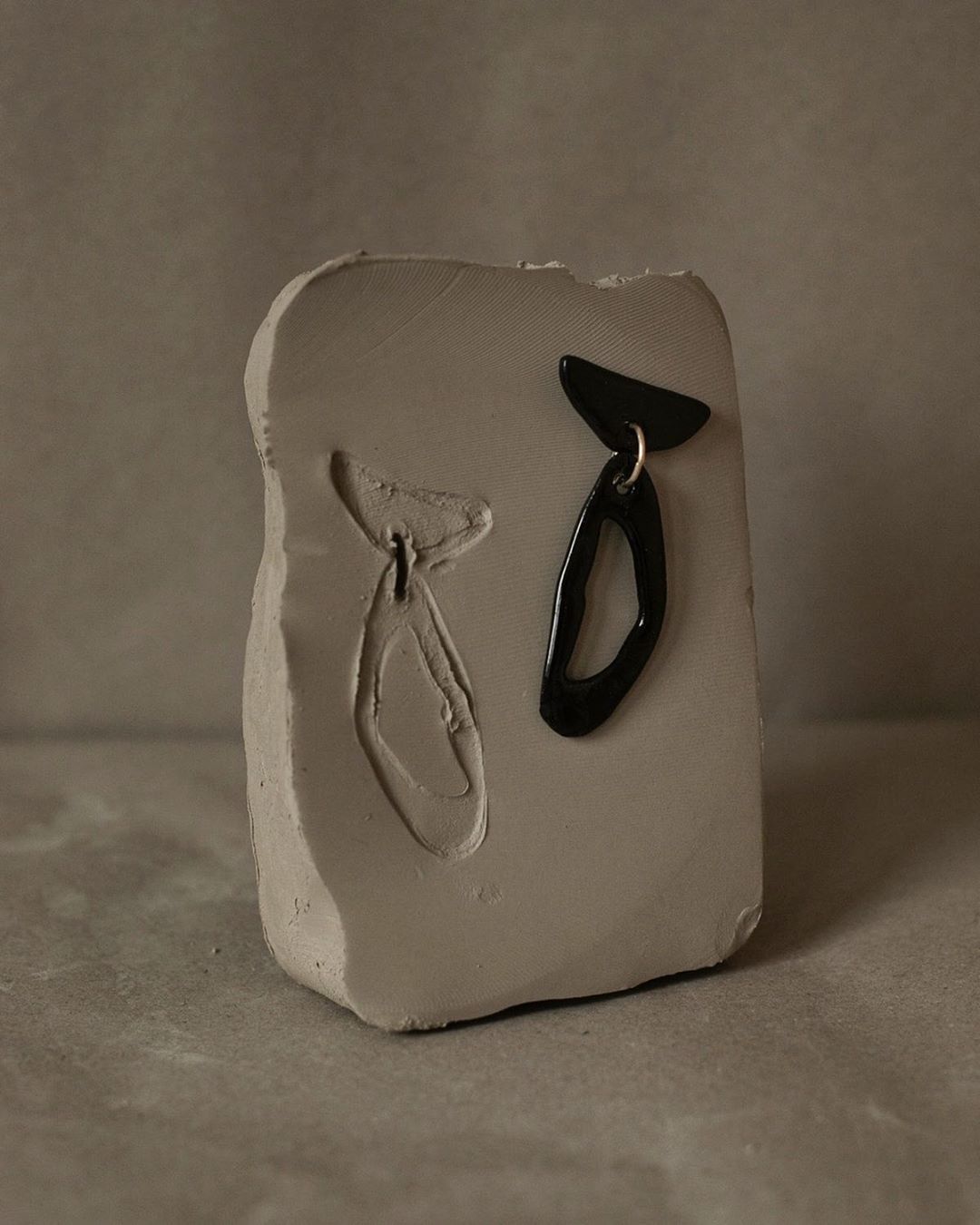 Black abstract ceramic sculpture with matching mold on a grey stone surface photographed by Anna Rosa Krau.