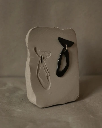 Black abstract ceramic sculpture with matching mold on a grey stone surface photographed by Anna Rosa Krau.