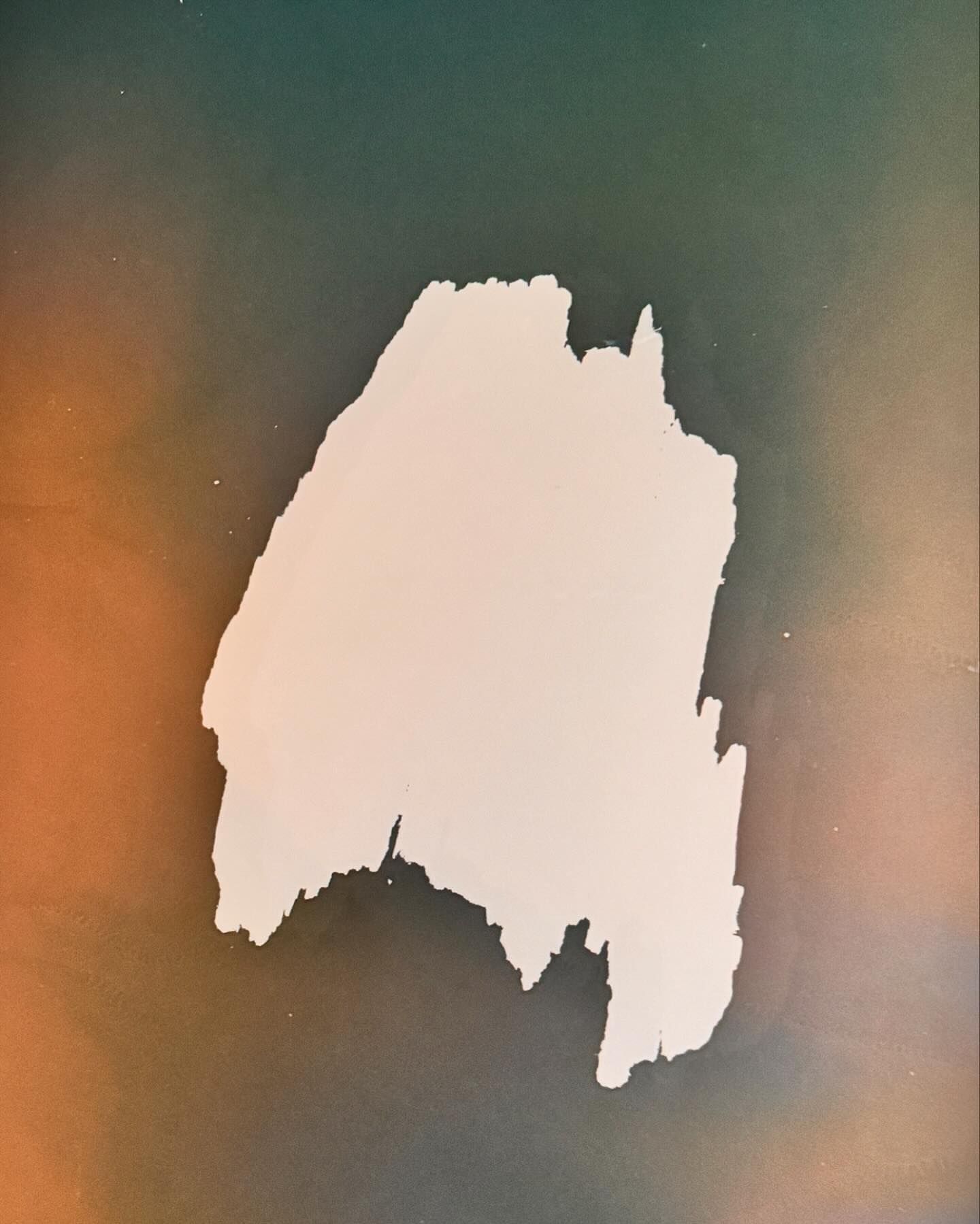 Abstract shot of a textured white irregular shape set against a blended background of green, blue, and orange tones.