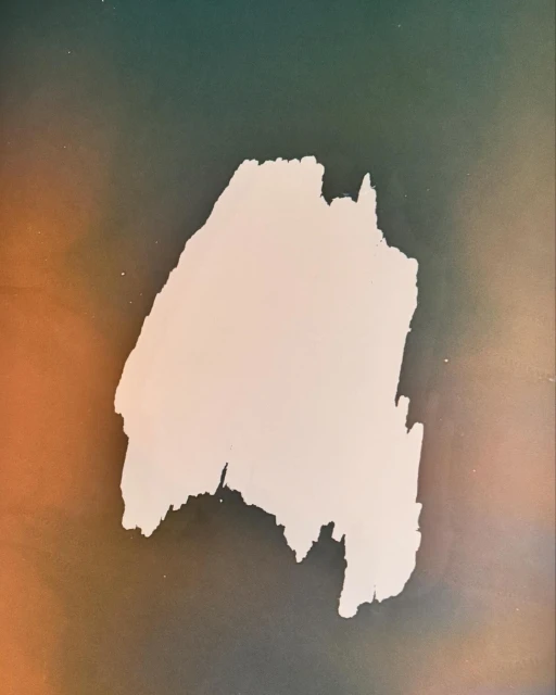 Abstract shot of a textured white irregular shape set against a blended background of green, blue, and orange tones.