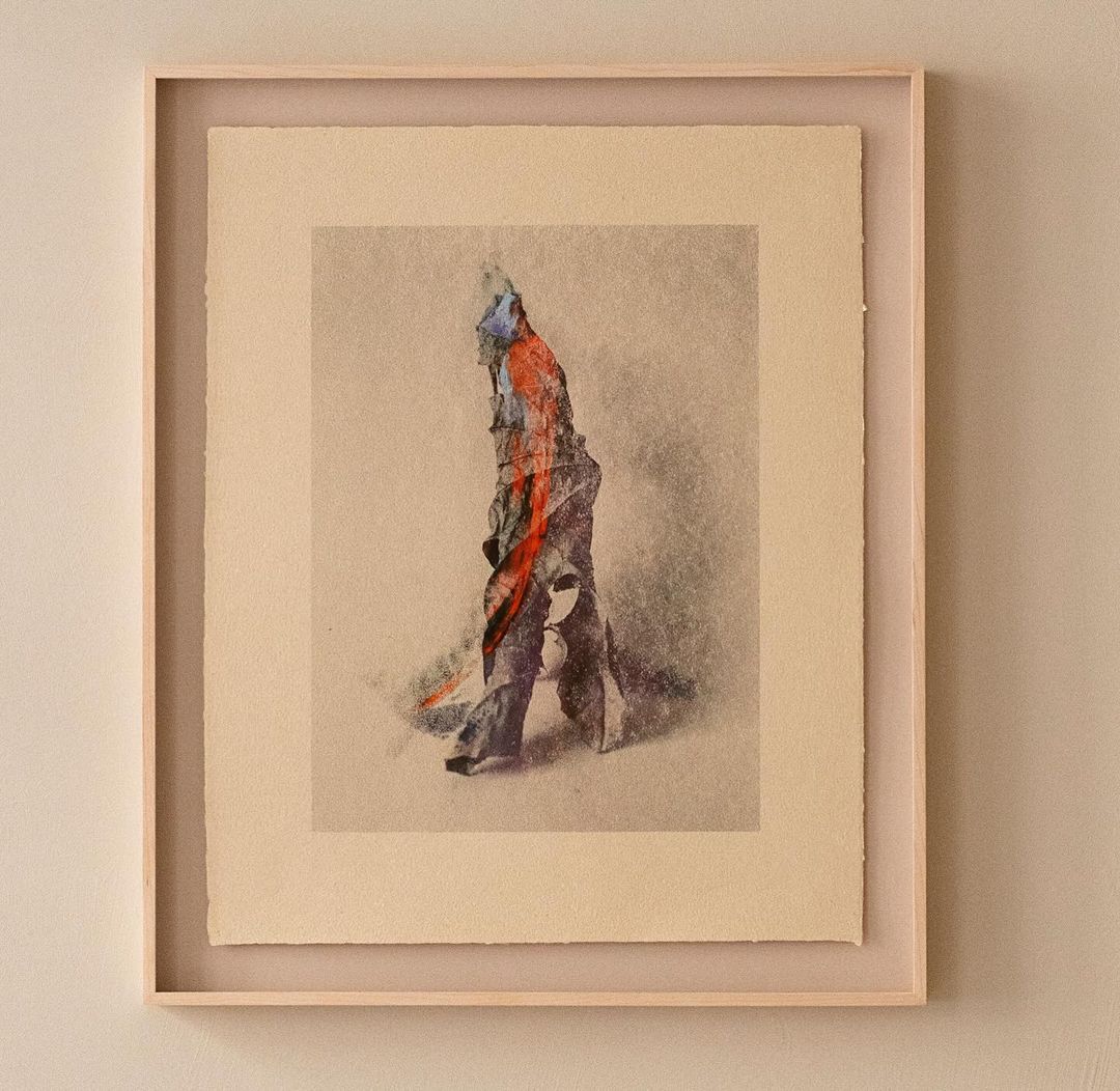 An abstract painting of a figure with vibrant colors in a wooden frame, showcased against a neutral wall, enhancing its artistic presence.