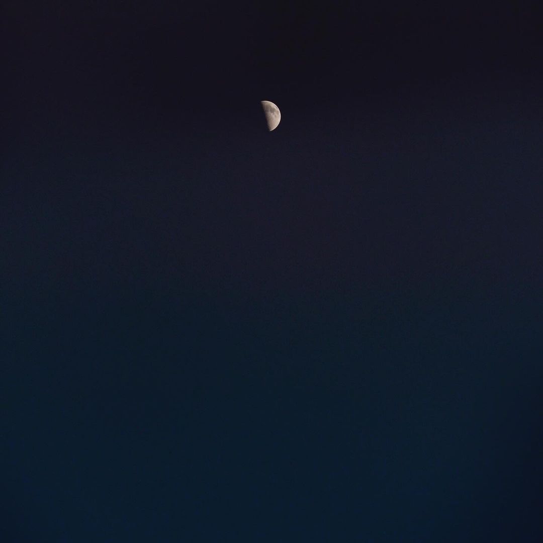 Night sky featuring a crescent moon against a gradient dark blue backdrop, creating a serene and minimalist celestial scene.