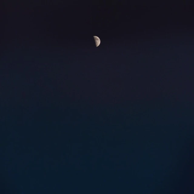 Night sky featuring a crescent moon against a gradient dark blue backdrop, creating a serene and minimalist celestial scene.