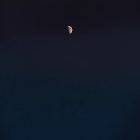 Night sky featuring a crescent moon against a gradient dark blue backdrop, creating a serene and minimalist celestial scene.