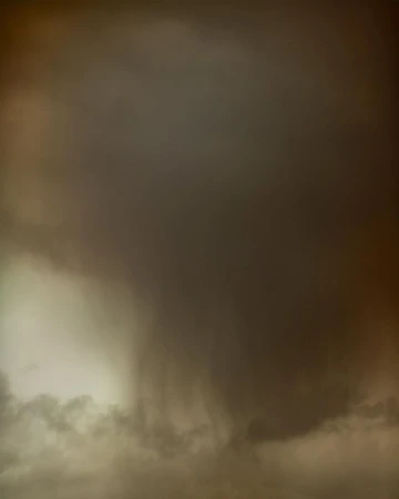 Dramatic cloudscape featuring dark, heavy storm clouds covering most of the frame with a patch of lighter clouds in the lower left corner.