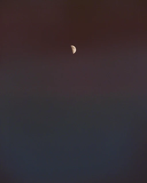 Crescent moon in the night sky against a dark gradient background. The lunar phase is the primary focal point.