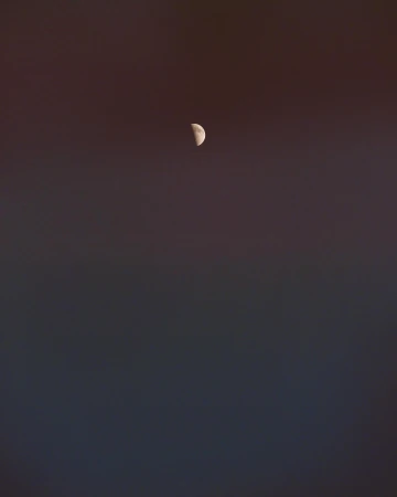 Crescent moon in the night sky against a dark gradient background. The lunar phase is the primary focal point.