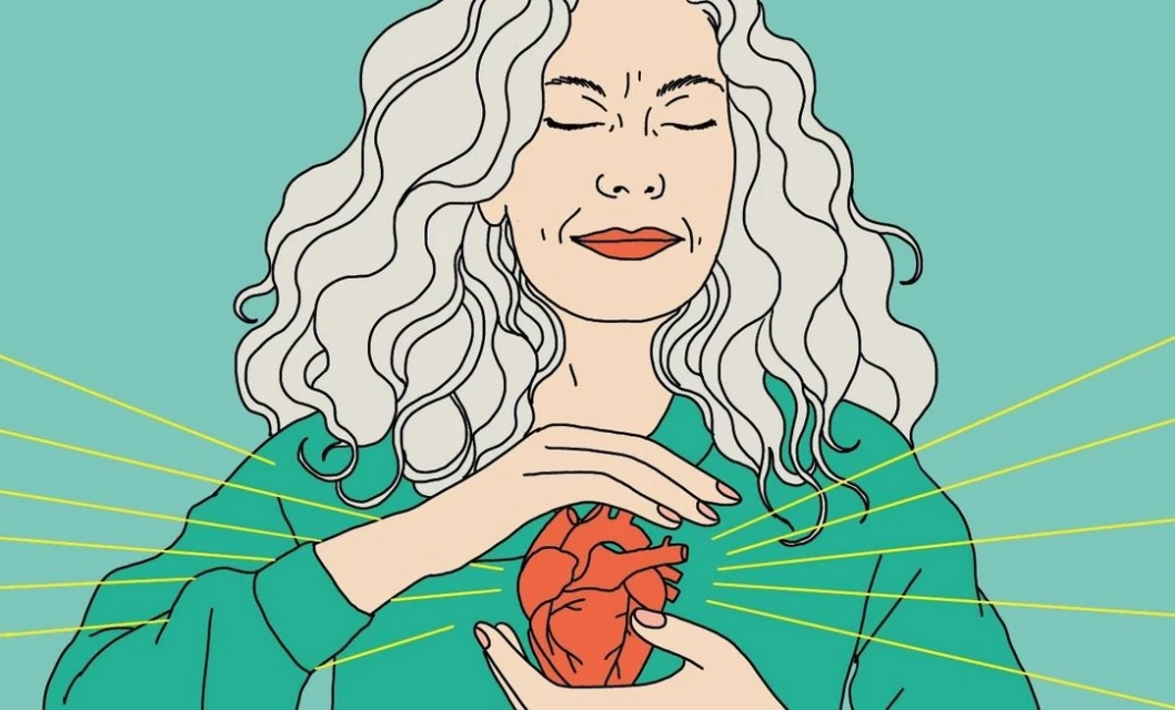 Illustration of a woman with white, wavy hair holding a red anatomical heart with yellow radiating lines on a teal background.