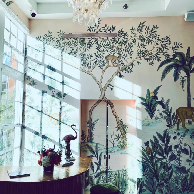 Bright and airy interior with a floral and wildlife mural, featuring palm trees, a monkey, and a flamingo statue on a counter.