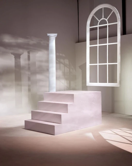 Architectural backdrop with stairs, column, and a window frame in a minimalist studio setting with soft, diffused lighting.