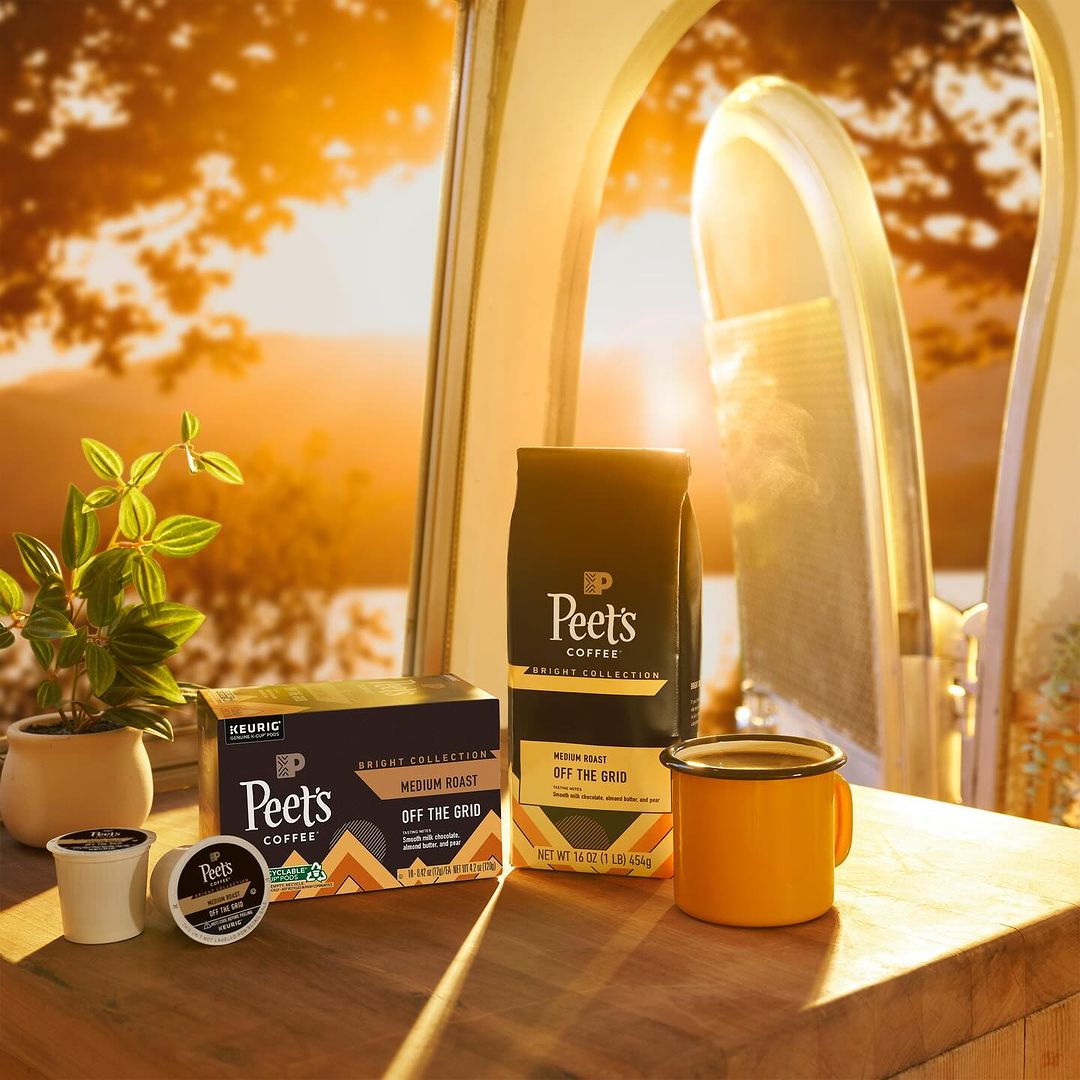 Peet's Coffee products including coffee bags and single-serve coffee pods are displayed next to a plant, bathed in warm sunlight.