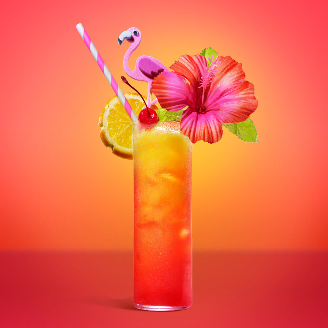 Vibrant tropical cocktail with a hibiscus flower, flamingo, orange slice, and cherry, set against a warm gradient background.