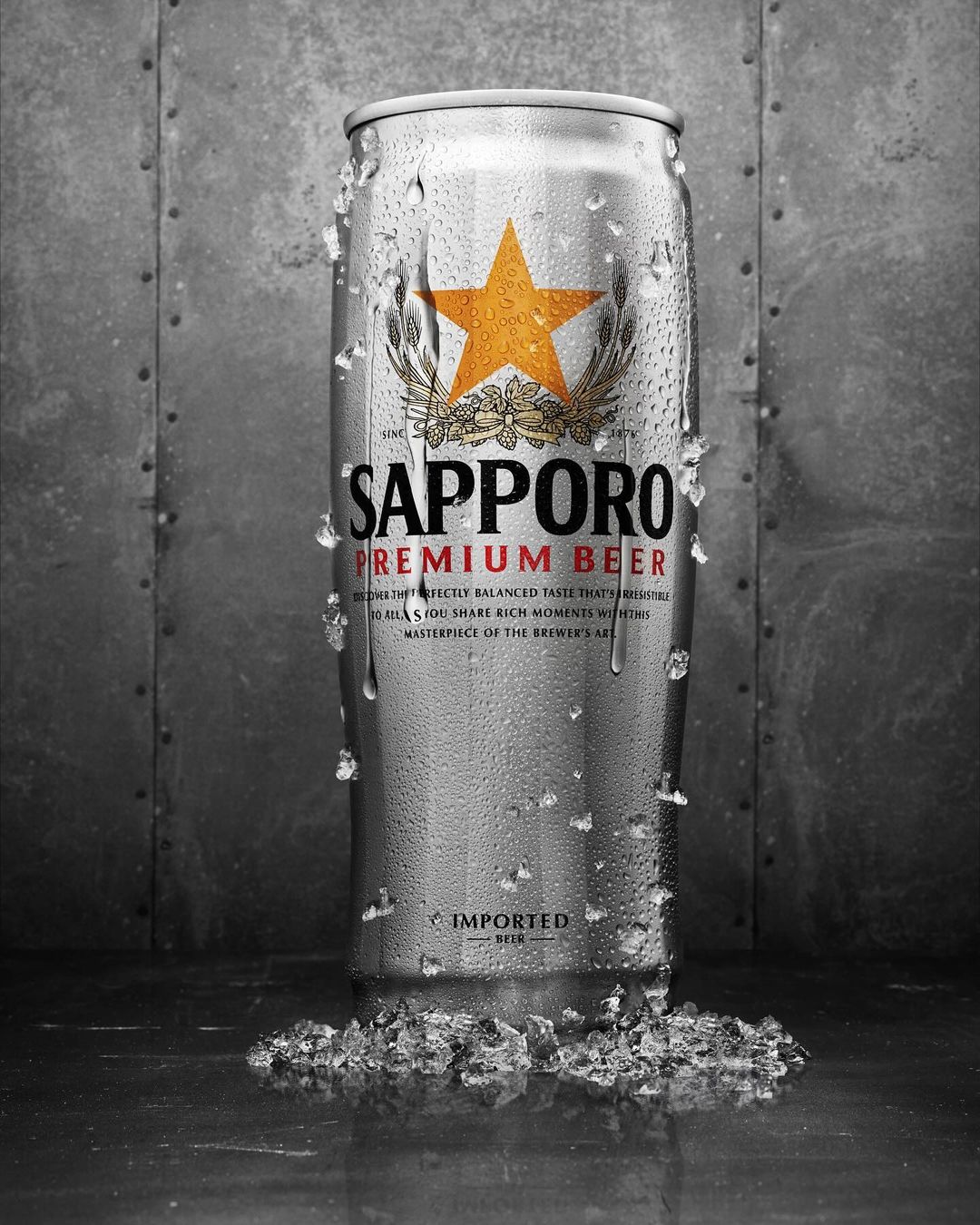 Sapporo Premium Beer can with condensation and ice crystals, set against a textured grey background. Product shot, food and beverage.